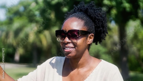 African female adult in sunglasses enjoying a sunny day outdoors.