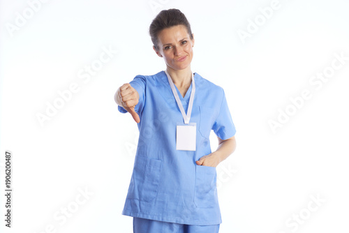 Foto A female nurse in medical scrubs gives a thumbs-down gesture with a disappointed look, representing health warnings, rejection, or negative test results