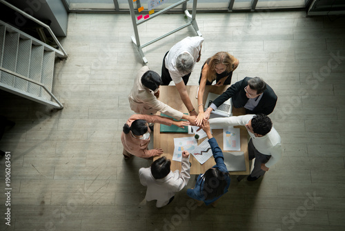 Wallpaper Mural Top view of a multicultural business team stacking hands together over a meeting table, symbolizing unity Torontodigital.ca