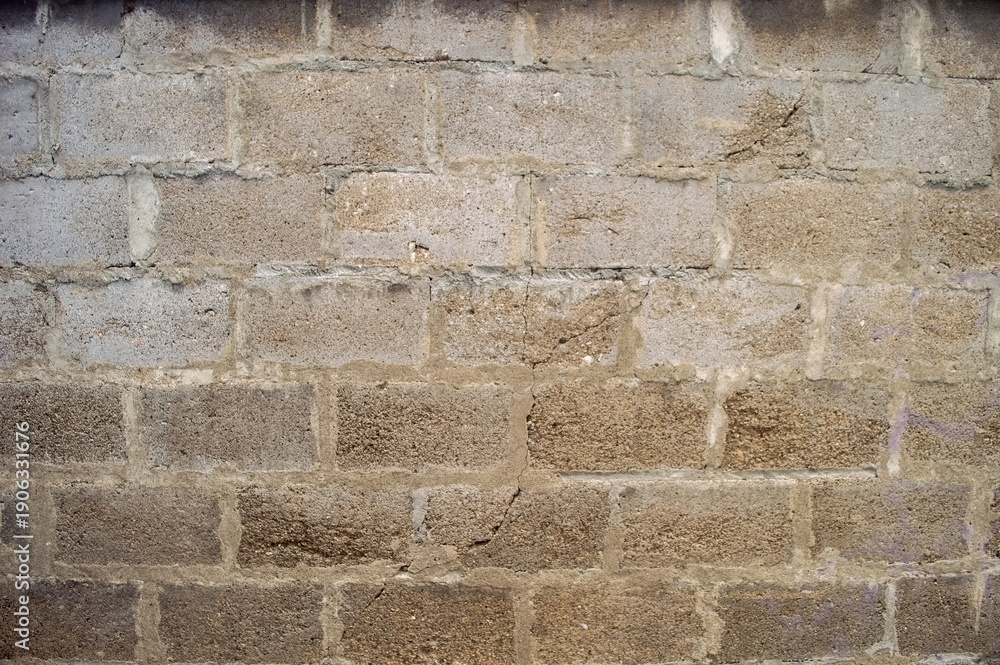 Fototapeta premium A close up of a weathered grey concrete cinder block wall texture, showing its rough surface and grout lines, perfect for architectural or urban design projects