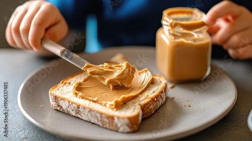 A child spreads creamy peanut butter on a slice of bread