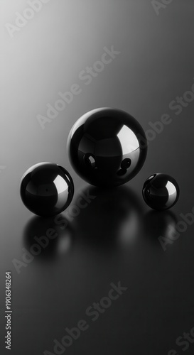 Three highly polished, dark spheres rest upon a reflective, dark surface with soft gradient lighting.