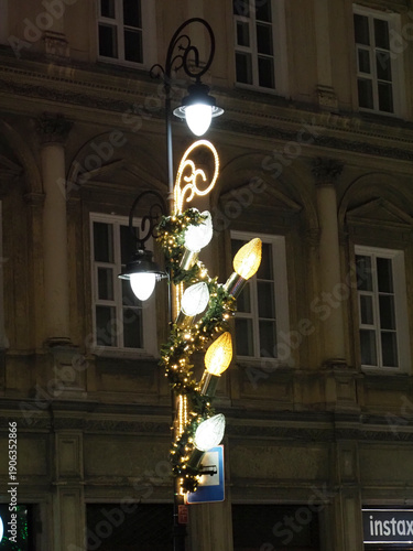 Close up of festive street lamp decorated with golden ornaments and lights at night