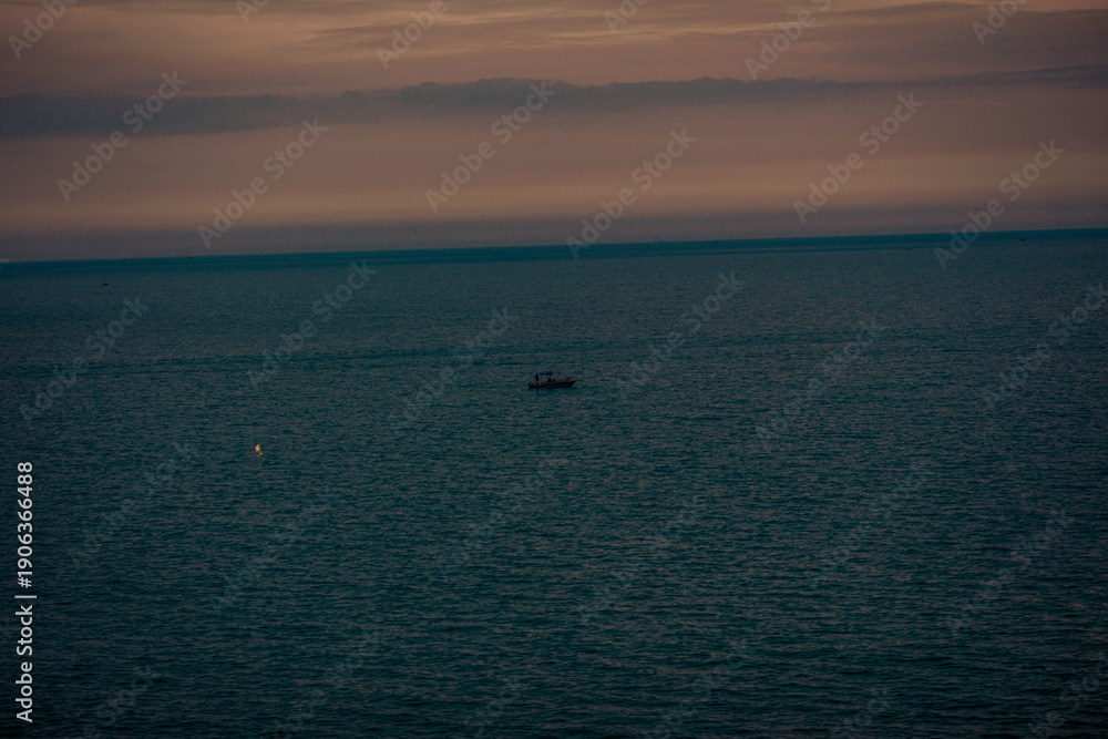 Fototapeta premium The background of the sea by the evening sea, with natural beauty (sea water, rocks, sky) and fishermen are fishing by the river bank, is a pleasure during travel.
