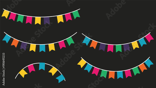 Multiple strings of colorful bunting flags in various shapes and colors hanging against a dark black background for celebrations.