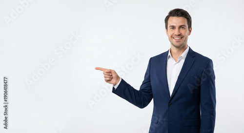 Wallpaper Mural Smiling businessman in a blue suit points to the left with copy space on a clean white background. Torontodigital.ca