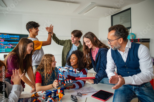 Diverse high school team building robotic arms during science class.