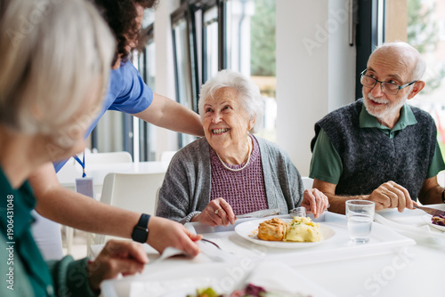 фотографія Caregiver serving lunch to elderly residents in a care home.