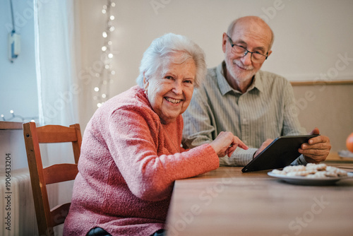 Senior coule working with tablet, making reservation or shopping online.