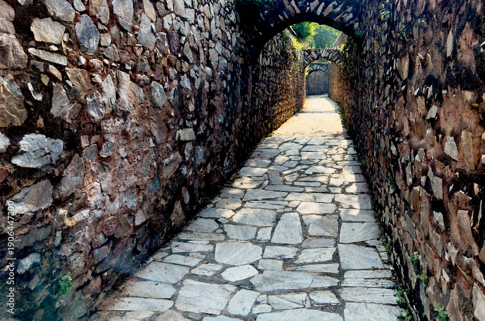 Fototapeta premium Narrow stone passage with arched openings and rough masonry walls inside a historic fortress.