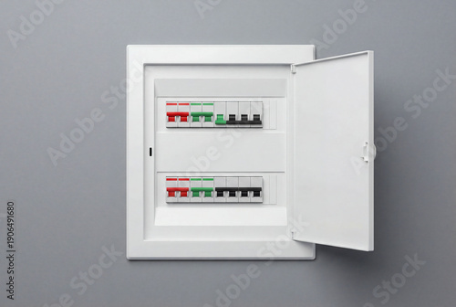 White electrical consumer unit with circuit breakers on a gray wall