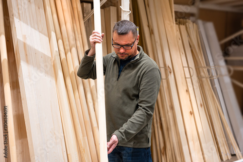 Man selecting timber (wooden lath) in hardware store