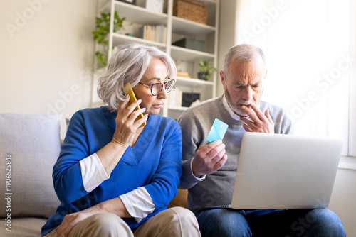 Worried senior couple making online payment using credit card and laptop