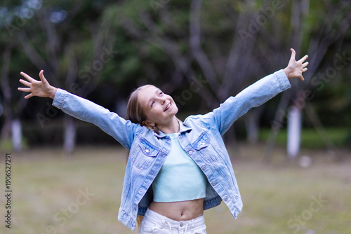 Happy girl with outstretched arms enjoying nature in a park