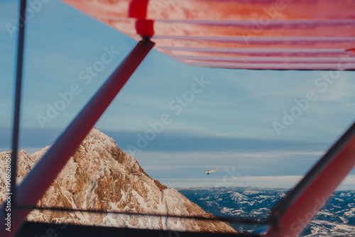 Jagged mountain peaks appear through the structure of a small plane.