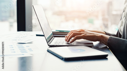 都市のオフィスビルでノートパソコンとタブレットPCを使って作業する女性ビジネスパーソン