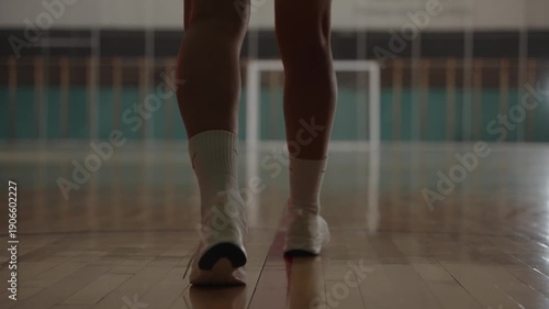 Back view of professional handball athlete running and throwing ball into empty net