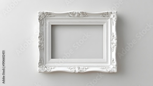 Elegant empty white rectangular picture frame featuring ornate carvings and a textured border shown in a well lit studio setting against a plain white wall ideal for design mockups or showcasing art
