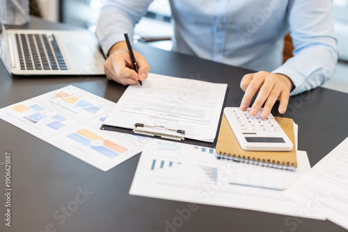 Fotografie Person working on financial documents, utilizing a calculator for calculations,