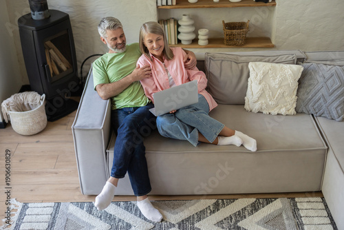 фотографія Older adults relaxing on couch looking at laptop screen