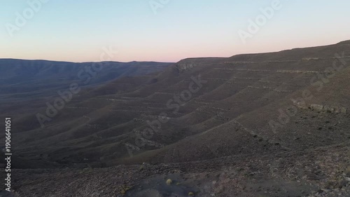 Camera panning from the ridge of the Roggeveld mountain range to the Ouberg pass and sunset on the horizon. 4K Aerial Video.