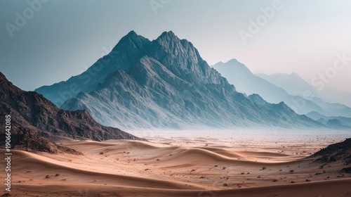 Dramatic desert landscape with mountains and sand dunes under a hazy sky