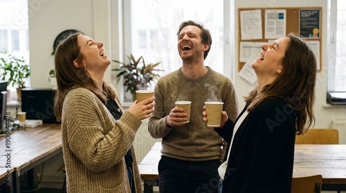 Colleagues laughing together during coffee break in office