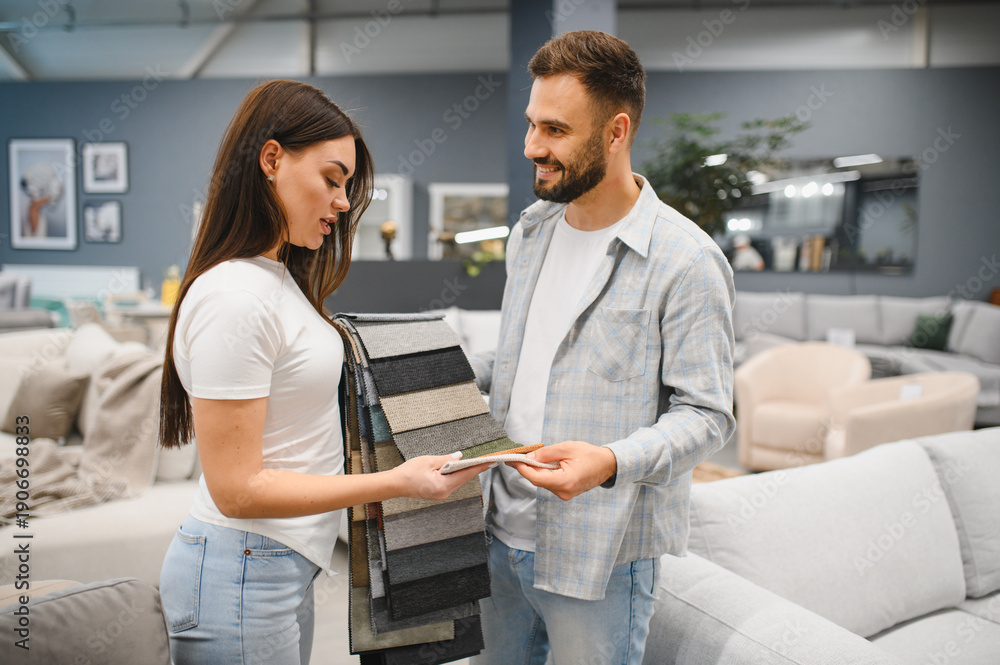 Obraz premium Couple choosing upholstery fabric samples in furniture store