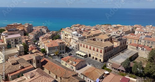 Panoramic aerial view of the historic center of Tropea, in province of Vibo Valentia, Calabria, southern Italy. The town is perched on a cliff overlooking the deep blue sea. Mediterranean landscape.