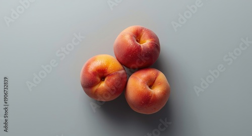 Glossy juicy peaches resting on an evenly toned subtle grey background