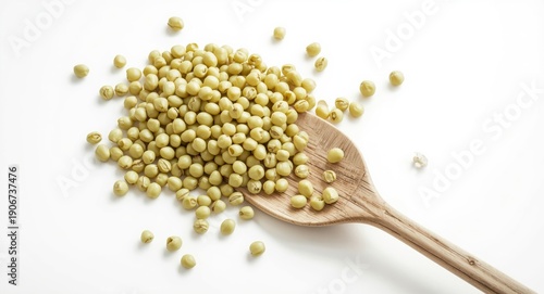 Fresh soybeans scattered on white surface with wooden spoon nearby