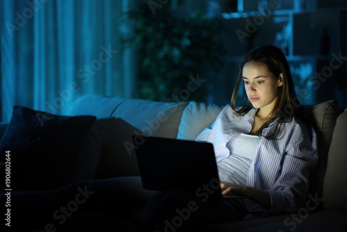 Serious woman using personal computer in the night at home