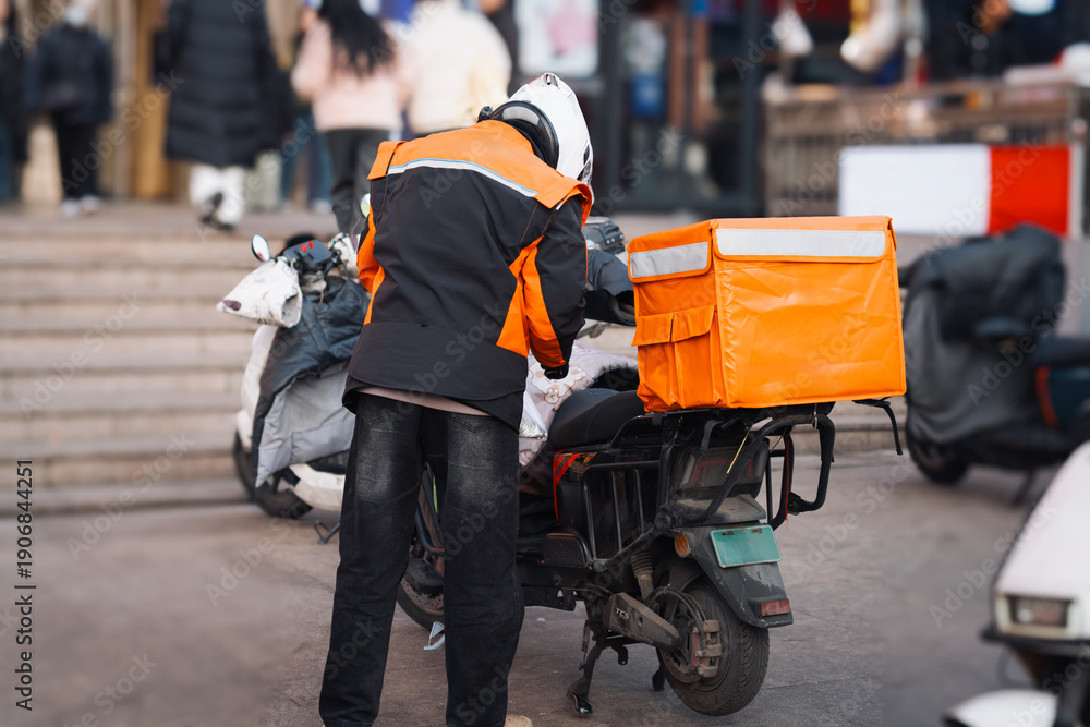 Obraz premium Delivery Worker with Orange Bag on Scooter