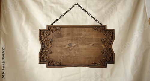 Decorated medieval wooden hanging signboard with ornate edges suspended by chain on simple white backdrop for heritage decor