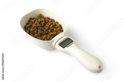 Pet Dry food in a digital spoon scale,, isolated on white.  Nutrition concept