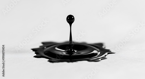 Wallpaper Mural A single drop of black liquid suspended above a splashing surface, captured in high-speed detail against a white background. Torontodigital.ca