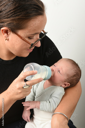 Mother with glasses feeding her baby a bottle