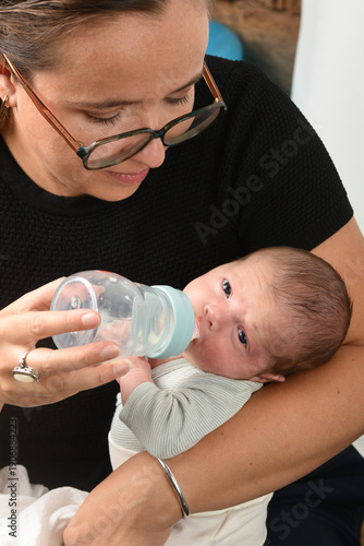 Mother with glasses feeding her baby a bottle