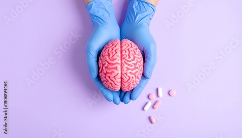 Hands in blue gloves cradle a pink brain model. Pills on lilac backdrop