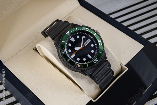 Luxury black diver wristwatch with green bezel and rubber strap in elegant gift box display