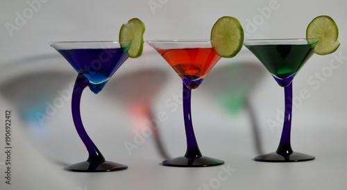 three blue stem Martini glasses with limes with red, blue and green cocktails with shadows
