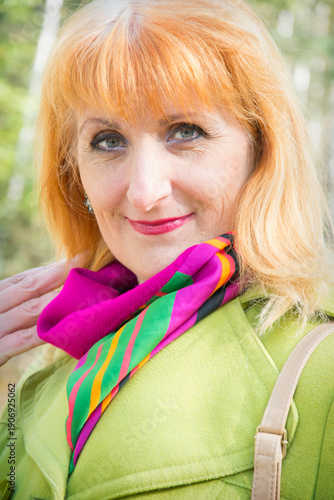 On a sunny autumn day in a birch forest there is a red-haired woman.