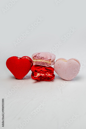Heart shaped macarons in red and pink colors with creamy filling arranged on a white background, symbolizing love, sweetness, and celebration for Valentine's Day