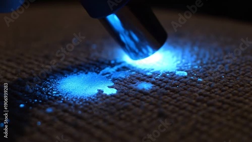 Criminal Law Restrictions concept. Close-up of a UV light detecting stains on a textured dark surface.