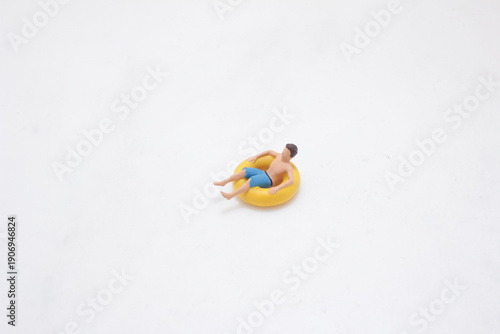 Miniature swimmer relaxes floating in yellow inflatable ring