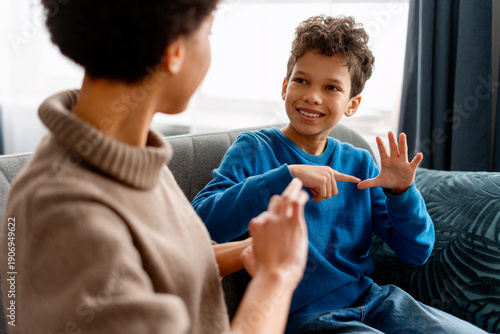 Slika na platnu Boy learning sign language with a woman, communicating with hand gestures