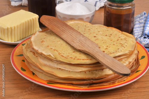 Assiette de crêpes bretonnes avec une spatule en bois, du beurre, du sucre, de la confiture et du caramel