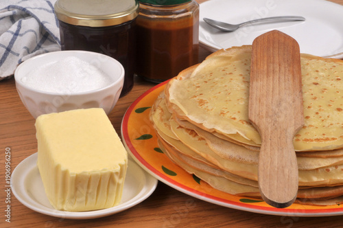 Assiette de crêpes bretonnes avec une spatule en bois, du beurre, du sucre, de la confiture et du caramel