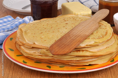 Assiette de crêpes bretonnes avec une spatule en bois, du beurre, de la confiture et du caramel