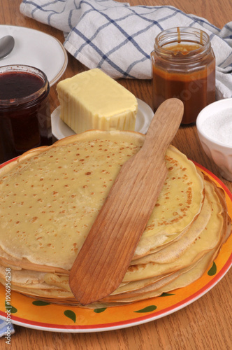 Assiette de crêpes bretonnes avec une spatule en bois, du beurre, du sucre, de la confiture et du caramel